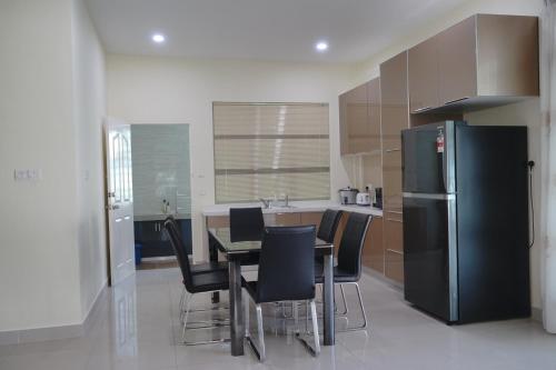 a kitchen with a table and chairs and a refrigerator at Likas House @ Alawa Homes in Kota Kinabalu