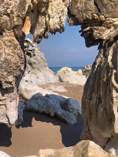 a view of the ocean through a rock formation at Villa Delfini in Chrani