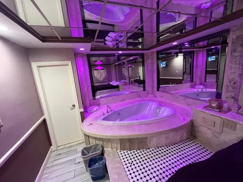baño grande con 2 bañeras con iluminación morada en Gallery Holiday Motel, en South Amboy