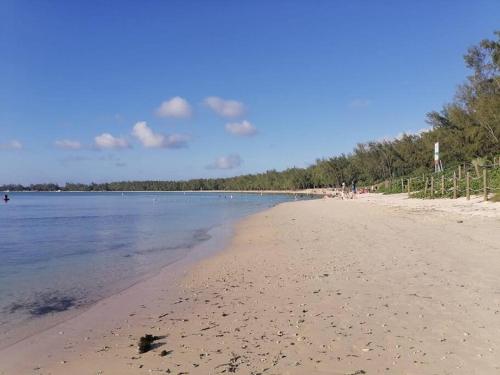 una playa de arena con gente caminando por el agua en Peaceful Nest in Mont Choisy en Grand Baie