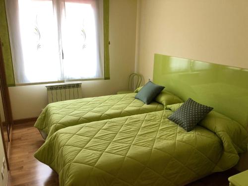twee bedden met groene lakens in een kamer bij Logroño: Piso con Garaje y Piscina. in Logroño