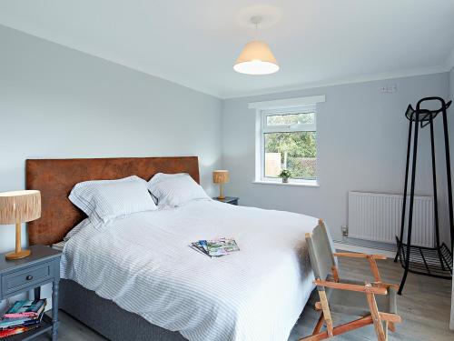 a bedroom with a large white bed with a wooden headboard at Tor Cottage in Exeter