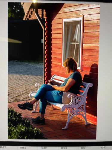 a woman sitting on a bench in front of a house at Blockhütte M o e r e n h o f Xanten in Xanten