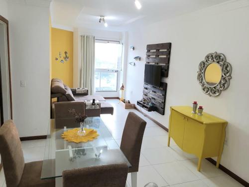 a dining room and living room with a glass table at Apartamento em Guarapari in Guarapari