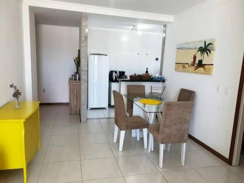 a kitchen with a table and chairs and a refrigerator at Apartamento em Guarapari in Guarapari