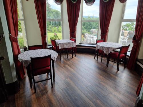 a dining room with tables and chairs and windows at Tyr Graig Castle in Barmouth