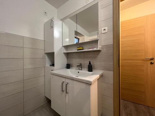 uma casa de banho com um lavatório branco e um espelho. em Mici's Apartments em Visoko