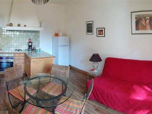 une cuisine avec un canapé rouge et une table en verre dans l'établissement Appartement T2 RDC à 100m de la plage avec terrasse et jardinet - 4 couchages - FR-1-388-1, à Argelès-sur-Mer