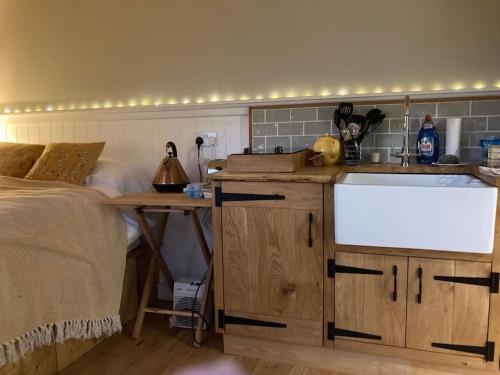 a kitchen with a sink and a bed in a room at Aspen Leaves: The perfect farm retreat in Graffham