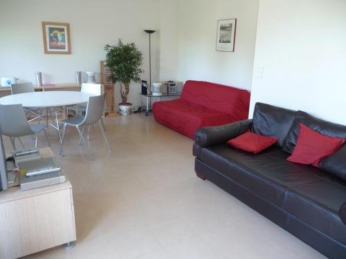 a living room with a red couch and a table at Appartement Ranavalo Pays Basque in Anglet