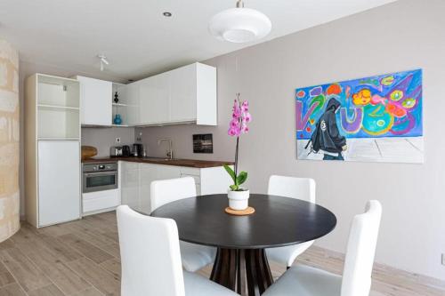 une cuisine avec une table, des chaises blanches et un tableau dans l'établissement EasyLodge - Appartement 2 chambres Bordeaux, à Bordeaux