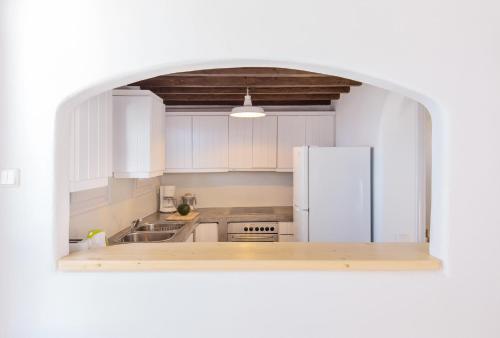una cucina con mobili bianchi e un frigorifero bianco di Villa Phaedra by Whitelist Mykonos ad Agios Ioannis