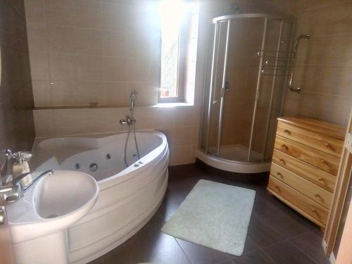 a bathroom with a tub and a shower and a sink at SKI&SUN - Apartmán B11 in Liptovský Mikuláš