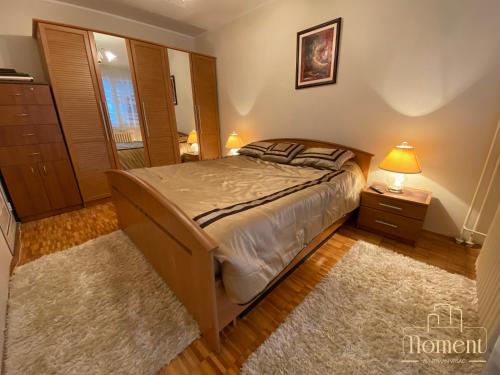 a bedroom with a bed with a lamp and a rug at Moment Apartman Vrsac in Vršac