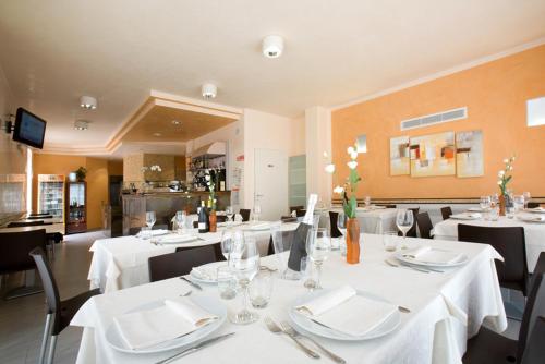 a dining room with white tables and black chairs at Hotel Ristorante Klaus in Porto Tolle