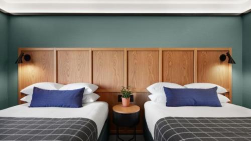 two beds with blue and white pillows in a room at Haworth Hotel at Hope College in Holland