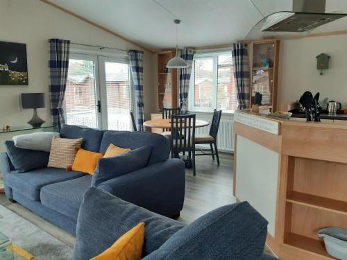 uma sala de estar com um sofá azul e uma cozinha em Sycamore Lodge Auchterarder em Auchterarder