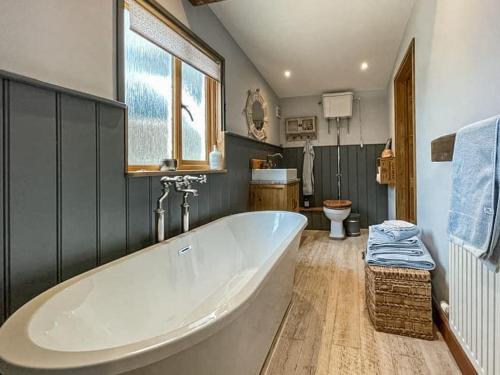 a large white tub in a bathroom with a toilet at The Nutshell. Rural retreat in Pluckley