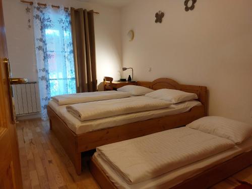 1 dormitorio con 3 camas y ventana en Bolfenk Apartment en Hočko Pohorje