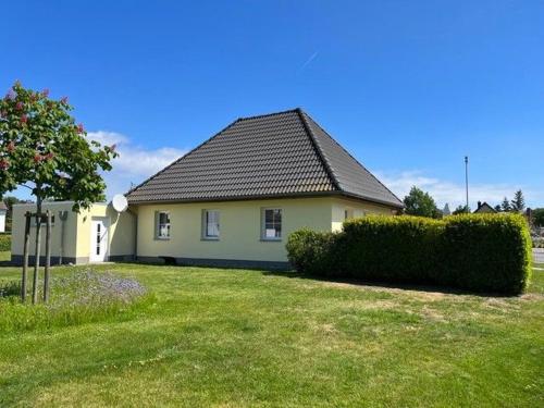 a yellow house with a black roof in a yard at Haus am NSG Baaber Heide in Baabe