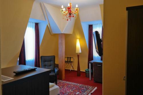 a living room with a chandelier and a room with a desk at Hotel Villa Glas in Erlangen