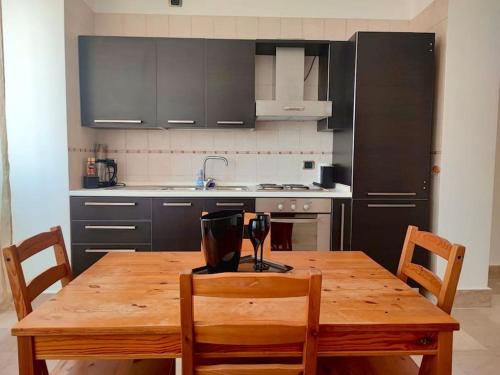 ローマにあるPorta Maggiore Houseの木製テーブルと椅子2脚、黒いキャビネット付きのキッチンが備わります。