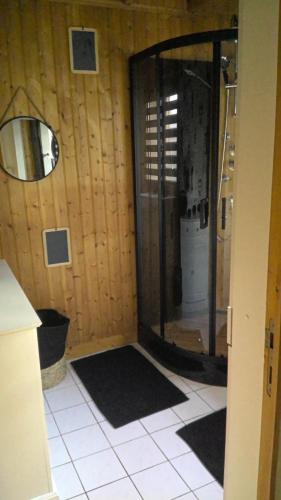 a bathroom with a shower with a mirror and a tile floor at CHALET BORD DE MER in Lingreville