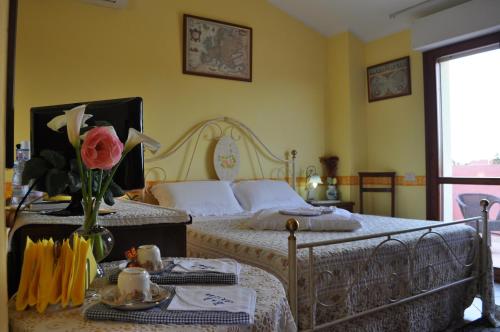- une chambre avec 2 lits et une table fleurie dans l'établissement Ariedo Bed And Breakfast, à Capoterra