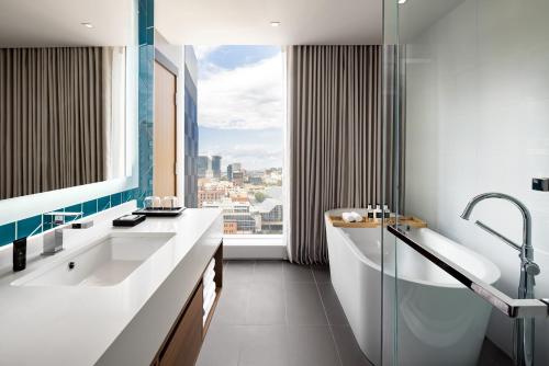 a bathroom with a tub and a sink and a window at Humaniti Hotel Montreal, Autograph Collection in Montréal