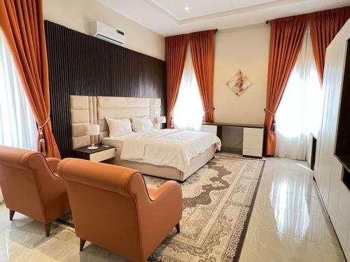 a bedroom with a bed and two chairs and a couch at Exquisite 5 Bedroom Villa in Kano in Kano