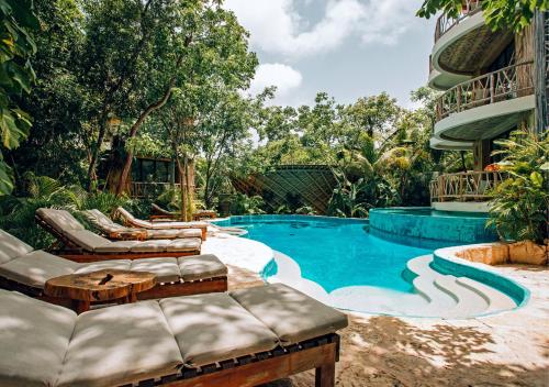 a swimming pool with lounge chairs next to a building at Kan Tulum in Tulum