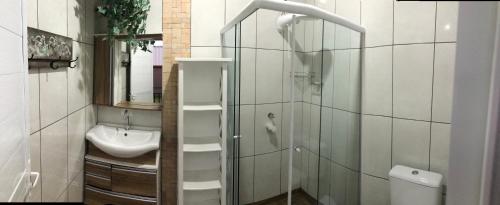 uma casa de banho com um chuveiro, um lavatório e um WC. em Pousada dos Adris em Morretes