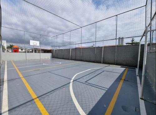 una pista de tenis con una valla y un aro de baloncesto en APARTAMENTO BC, en Balneário Camboriú