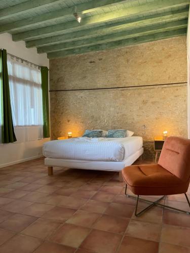 a bedroom with a bed and a chair at LAURAGUEL CHAMBRES D'HÔTES in Mourvilles-Hautes