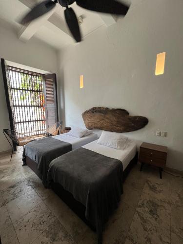 two beds in a room with a ceiling fan at Loft en Casa Colonial del Centro Histórico de Cartagena in Cartagena de Indias