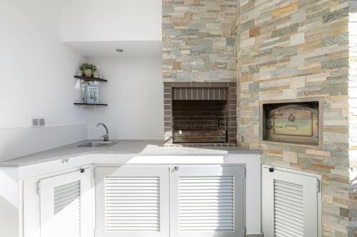 a kitchen with white cabinets and a stone fireplace at VILLA LIMOEIRO - Beautiful new home nestled in the heart of Galé in Guia