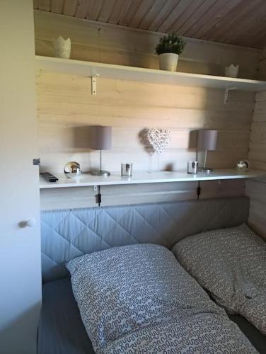 a room with a bed and a shelf with two lamps at Ferienhaus kleines Ostseeglück in Brodersby