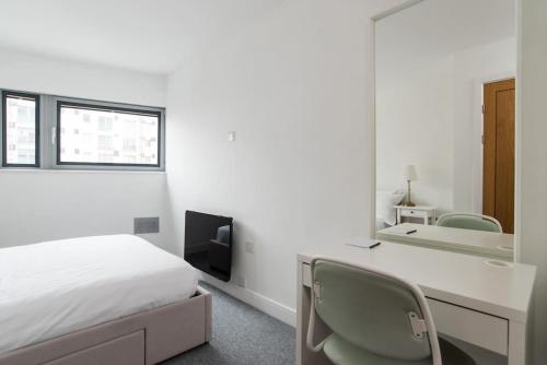 a bedroom with a bed and a desk and a mirror at Cardiff City Centre Apartment in Cardiff