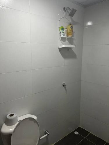 a white bathroom with a toilet and a shelf at Cabaña confortable y familiar in Coveñas