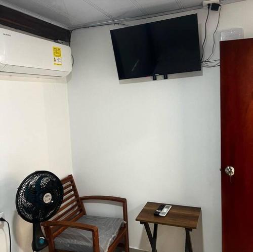 Zimmer mit einem Stuhl und einem TV an der Wand in der Unterkunft Cabaña confortable y familiar in Coveñas