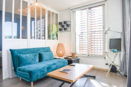 un salon avec un canapé bleu et une table dans l'établissement Bail mobilité - Studio cosy avec terrasse et vue, à Marseille