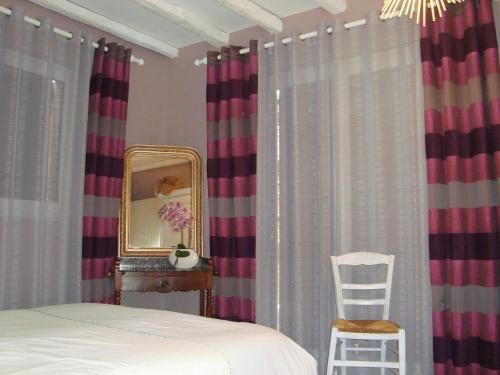 una camera con letto, specchio e sedia di Les Corneilles 