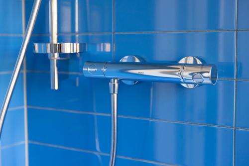 a shower head attached to a blue tiled wall at Strandhaus Hagen in Hagen