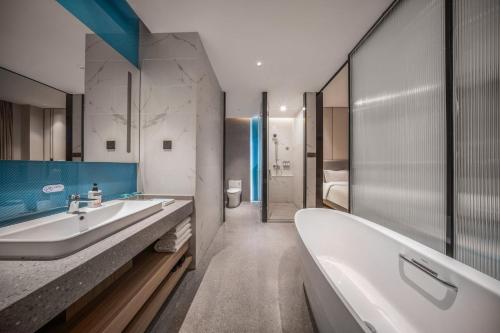 Holiday Inn Express Liaoyuan Economic Dev Zone, an IHG Hotel في Liaoyuan: حمام مع حوض ومغسلة وحوض استحمام