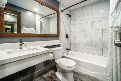 a bathroom with a toilet and a sink and a tub at Hotel Calle Joaquin - San Luis Obispo in San Luis Obispo