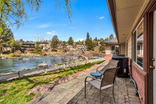 a patio with a table and a chair next to a river at Bend Riverside Condos Near Downtown Bend in Bend