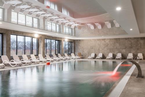 a swimming pool with white chairs and a fountain at Dziwnów River Side Apartment with Balcony by Renters Prestige in Dziwnów