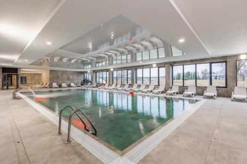 Una gran piscina con sillas en un edificio. en Lux Wellness Resort Apartments by the River by Renters Prestige, en Dziwnów