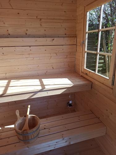 a wooden sauna with a window and a bucket at Ferienhaus kleines Ostseeglück in Brodersby OT Schönhagen