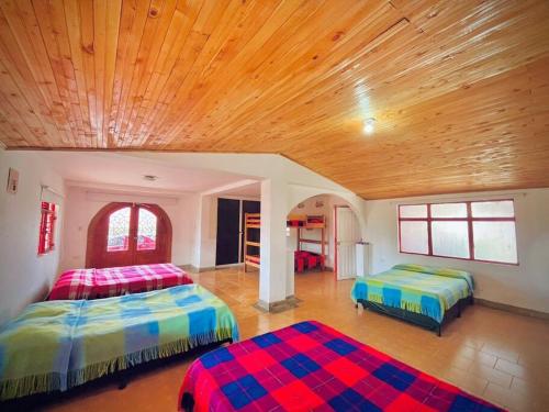 two beds in a room with a wooden ceiling at Hospedaje Finca Bella Vista in Santa Rosa de Cabal